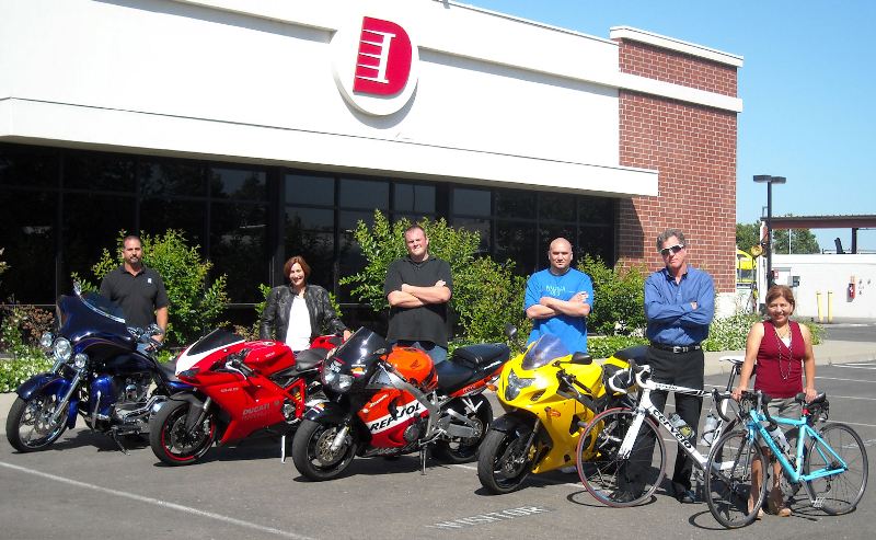 Staff members posing with their motorcycles and bicycles