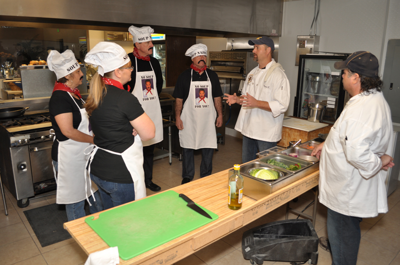 Staff members in kitchen listening to a chef