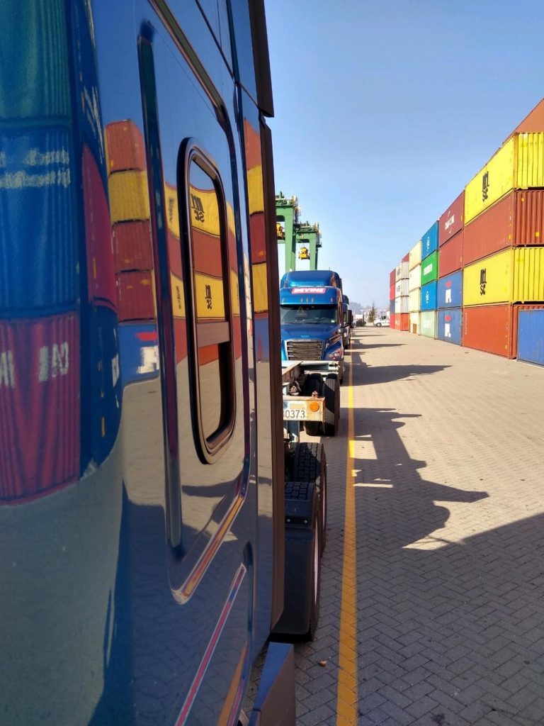 Blue Truck at the port with different color containers in the background