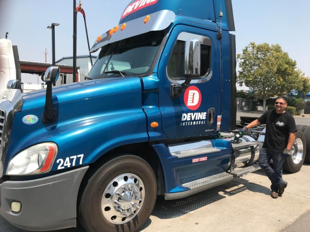 Blue truck refueling with the driver holding the dispense handle