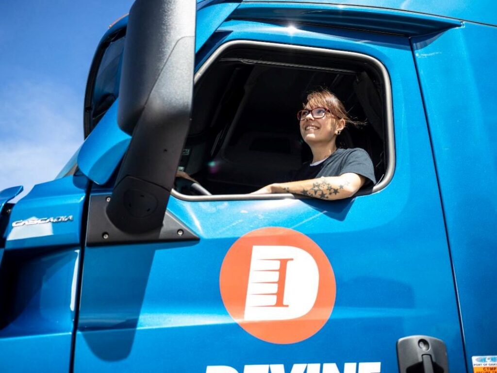 Women sitting in a blue truck driver seat.