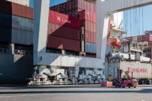 Picture of a crane at a port with containers in the background.