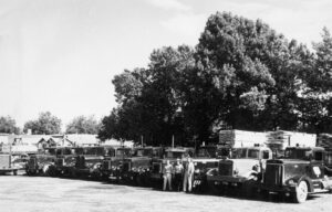 Black and white photo in 1950's. Show casing Devine growing fleet trucks.
